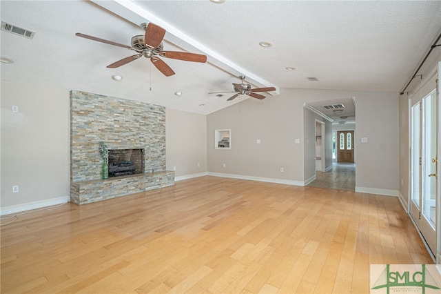 unfurnished living room with vaulted ceiling with beams, a fireplace, a textured ceiling, and light wood-type flooring