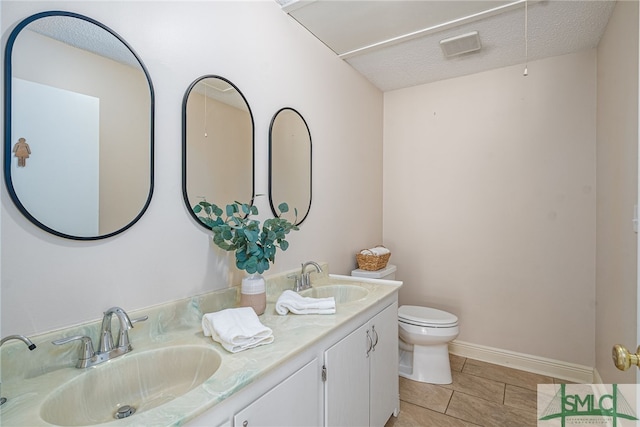 bathroom with tile patterned floors, vanity, toilet, and a textured ceiling