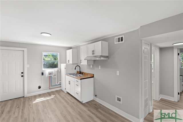 kitchen with butcher block counters, sink, light hardwood / wood-style flooring, and white cabinets