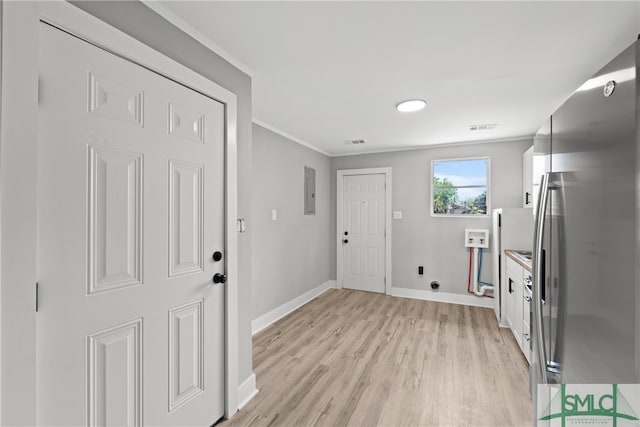 interior space with ornamental molding, light wood-type flooring, electric panel, stainless steel fridge, and white cabinets