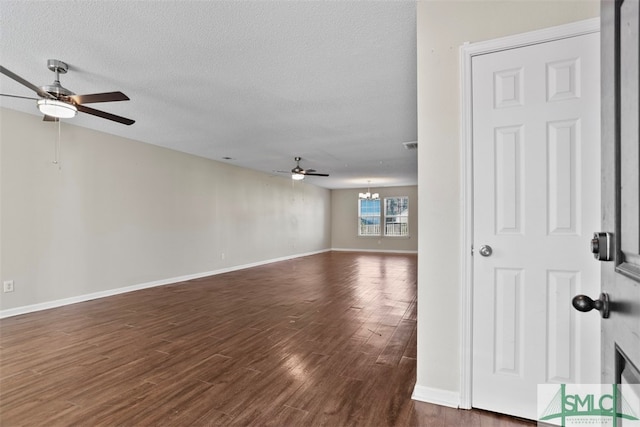 unfurnished room featuring a textured ceiling, ceiling fan with notable chandelier, and dark wood-type flooring