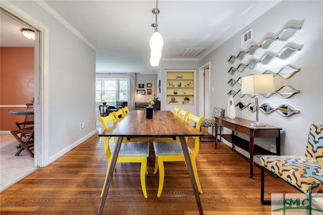 dining space with ornamental molding, dark hardwood / wood-style flooring, and built in shelves