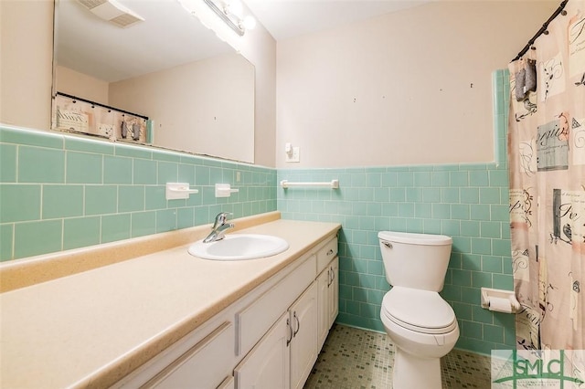 full bathroom with wainscoting, vanity, toilet, tile walls, and visible vents