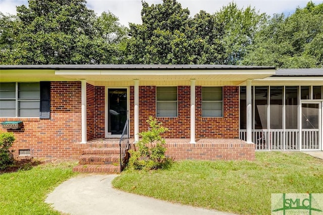 property entrance featuring a lawn, brick siding, and covered porch