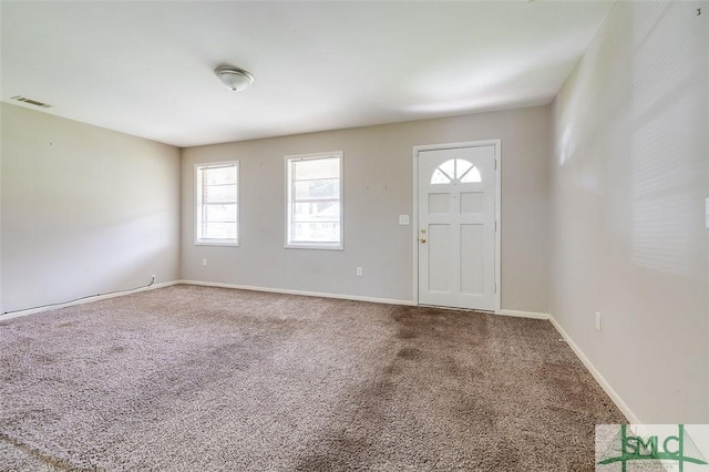 foyer entrance featuring baseboards, carpet flooring, and visible vents