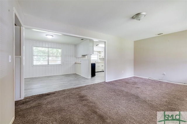 unfurnished living room featuring baseboards, visible vents, light carpet, and light wood-style floors