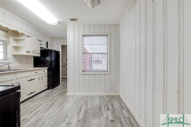 kitchen featuring light wood-type flooring, black appliances, sink, and white cabinets