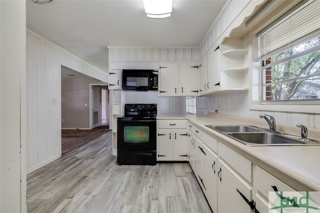 kitchen with light hardwood / wood-style flooring, black appliances, white cabinets, and sink