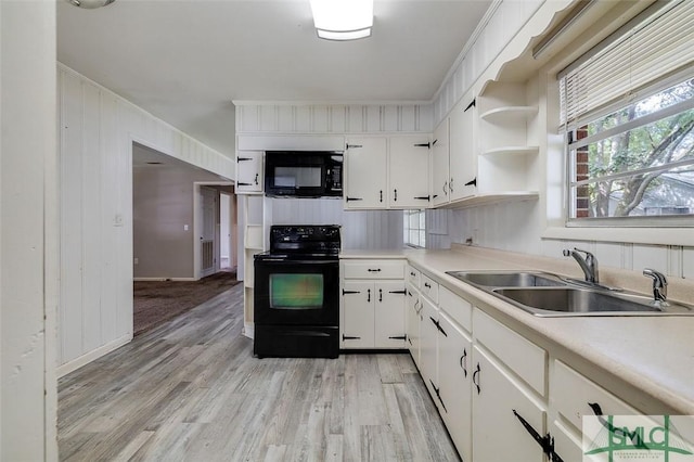 kitchen featuring a sink, light wood-style floors, black appliances, and white cabinetry
