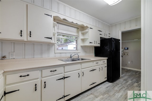 kitchen featuring light hardwood / wood-style floors, white cabinetry, sink, black fridge, and ornamental molding