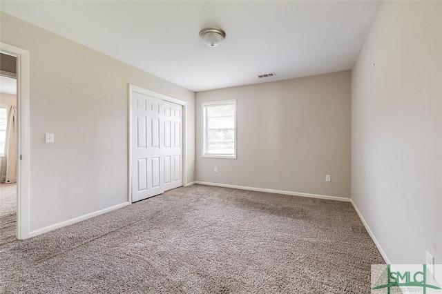 unfurnished bedroom featuring carpet floors, baseboards, a closet, and visible vents