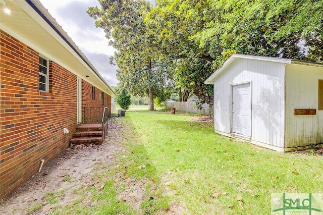 view of yard featuring an outdoor structure, central AC, and fence
