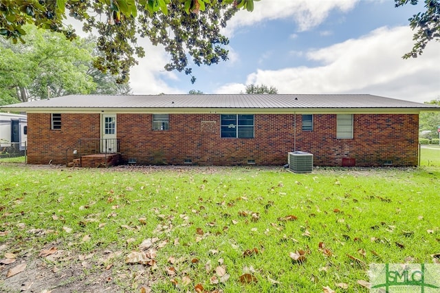 back of property with central AC and a lawn