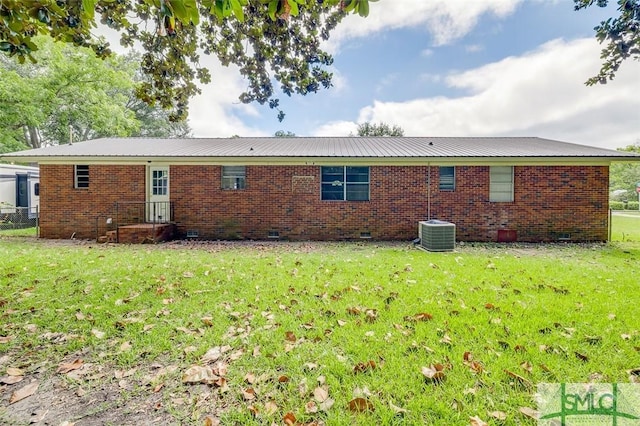 rear view of house with metal roof, a yard, brick siding, and crawl space