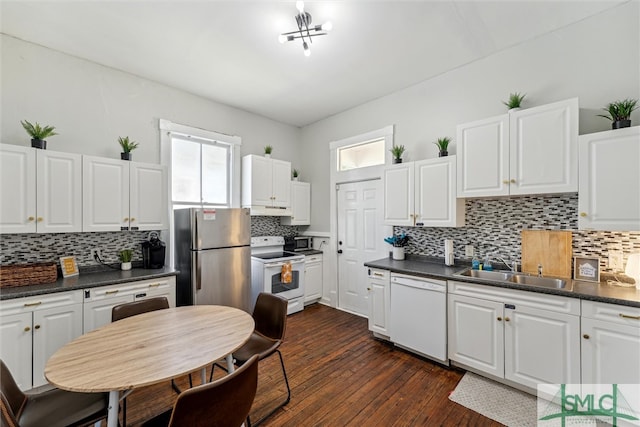 kitchen with white appliances, white cabinetry, sink, dark wood-type flooring, and decorative backsplash