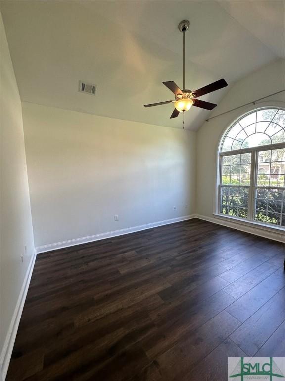 spare room featuring dark wood-style floors, ceiling fan, visible vents, and lofted ceiling