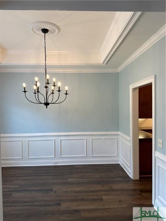 unfurnished dining area with ornamental molding, dark wood-style flooring, a wainscoted wall, and a notable chandelier