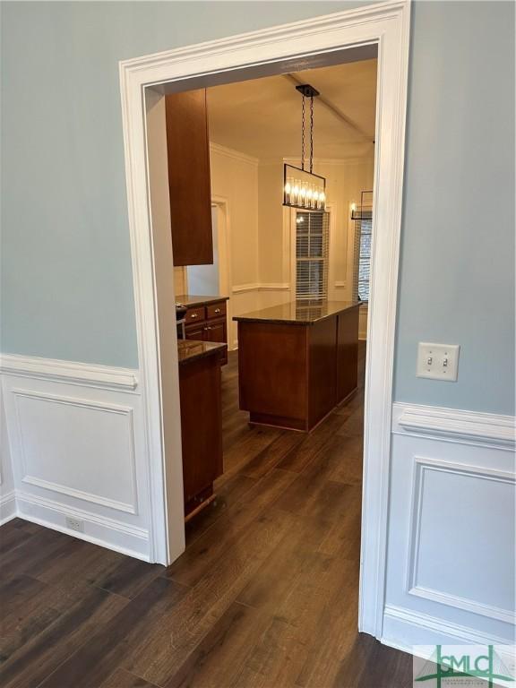 hallway featuring a notable chandelier, wainscoting, and dark wood-style flooring