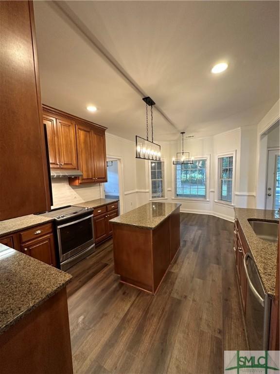 kitchen featuring a kitchen island, appliances with stainless steel finishes, dark wood finished floors, under cabinet range hood, and dark stone counters