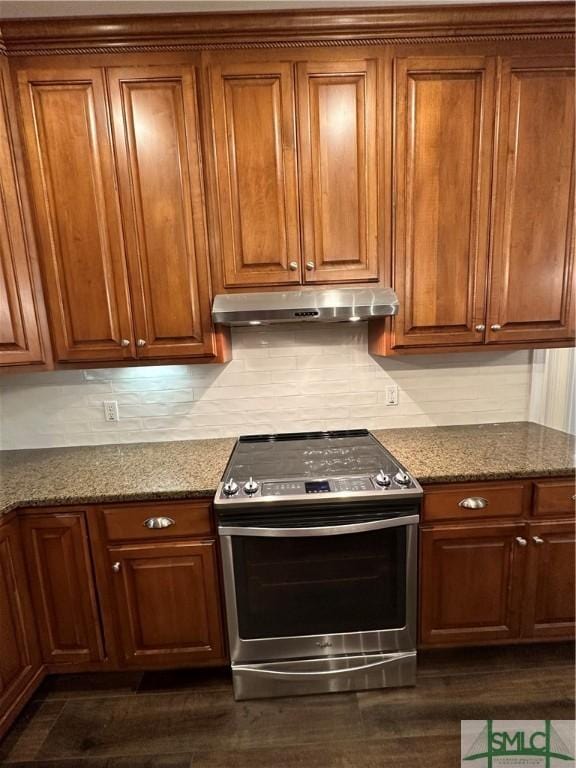 kitchen with stone counters, tasteful backsplash, brown cabinets, under cabinet range hood, and electric stove