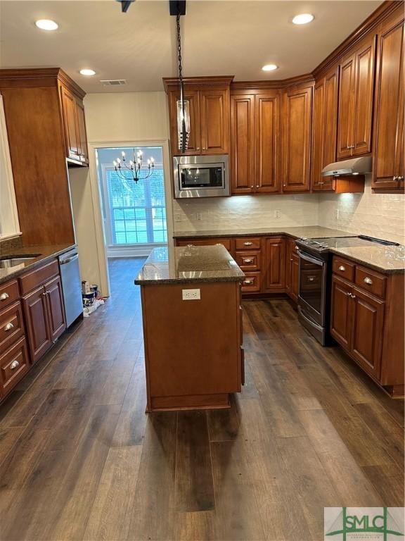 kitchen with visible vents, a chandelier, dark stone counters, appliances with stainless steel finishes, and under cabinet range hood