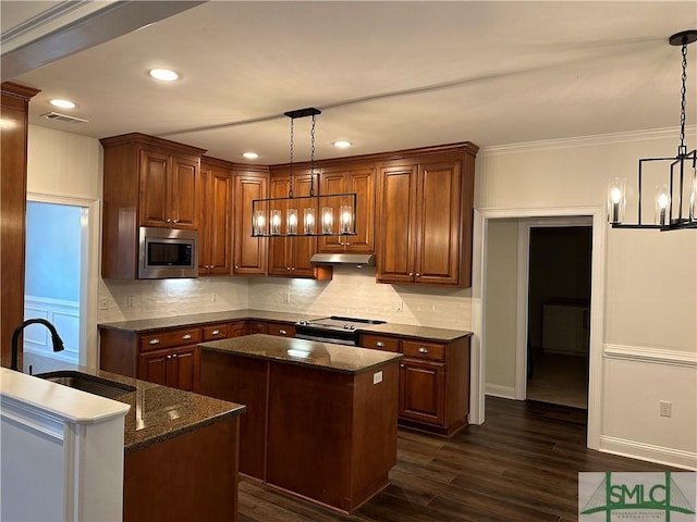 kitchen featuring under cabinet range hood, a chandelier, a kitchen island, visible vents, and appliances with stainless steel finishes
