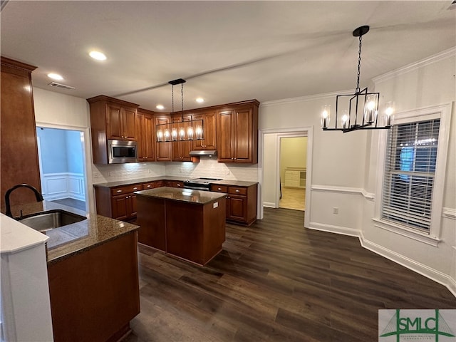 kitchen featuring a kitchen island, decorative light fixtures, appliances with stainless steel finishes, dark wood-type flooring, and sink