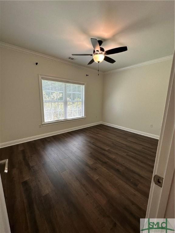 spare room featuring visible vents, crown molding, baseboards, a ceiling fan, and dark wood finished floors