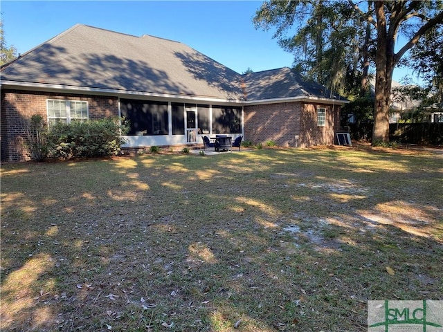 back of house with a lawn, a sunroom, and brick siding