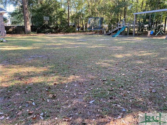 view of yard featuring playground community, fence, and a trampoline