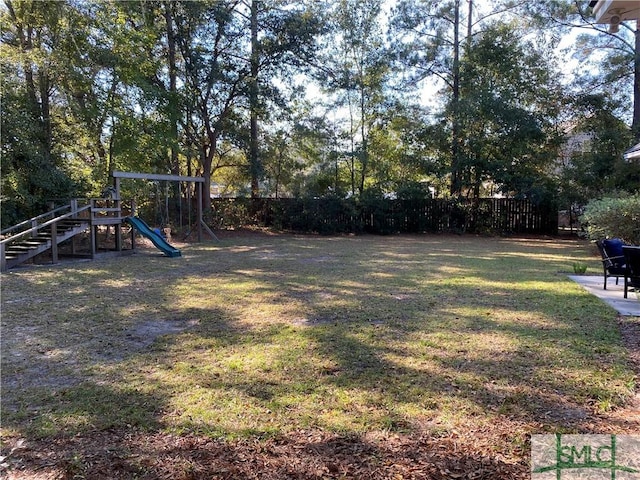 view of yard featuring playground community and fence