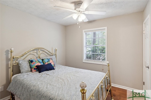 bedroom with ceiling fan, wood-type flooring, and a textured ceiling