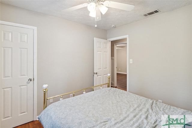 bedroom featuring hardwood / wood-style floors, ceiling fan, and a textured ceiling