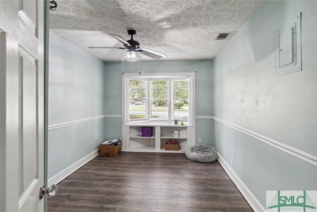 unfurnished room featuring dark wood-type flooring, ceiling fan, electric panel, and a textured ceiling