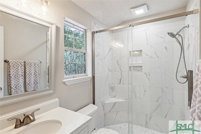 bathroom featuring a textured ceiling, a shower with shower door, toilet, and vanity