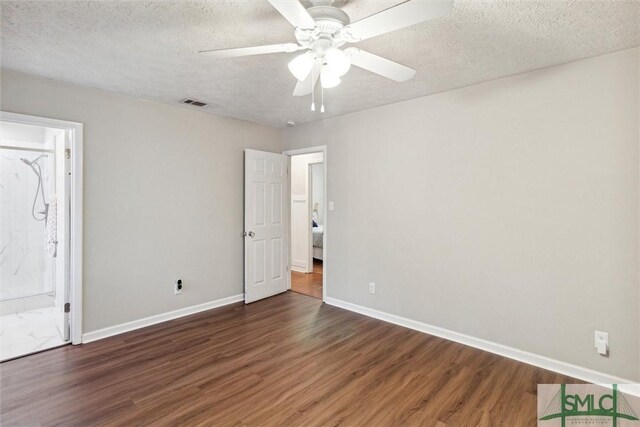 unfurnished bedroom with dark hardwood / wood-style flooring, connected bathroom, ceiling fan, and a textured ceiling