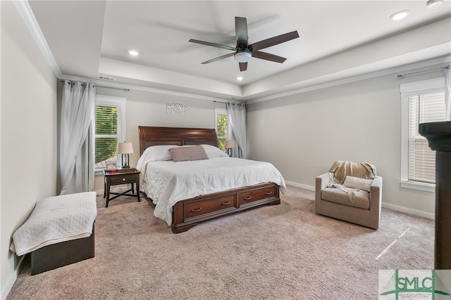 carpeted bedroom with multiple windows, ceiling fan, and a raised ceiling