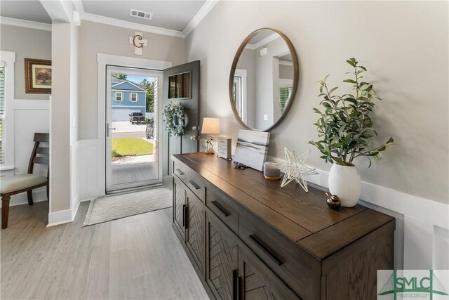 foyer featuring ornamental molding and light hardwood / wood-style floors