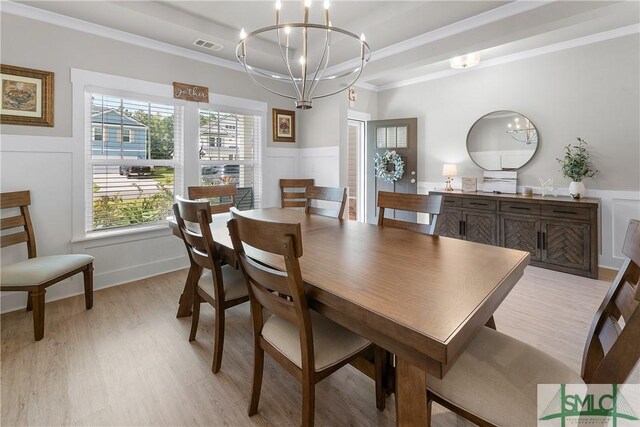 dining area with light wood-type flooring, ornamental molding, an inviting chandelier, and a healthy amount of sunlight