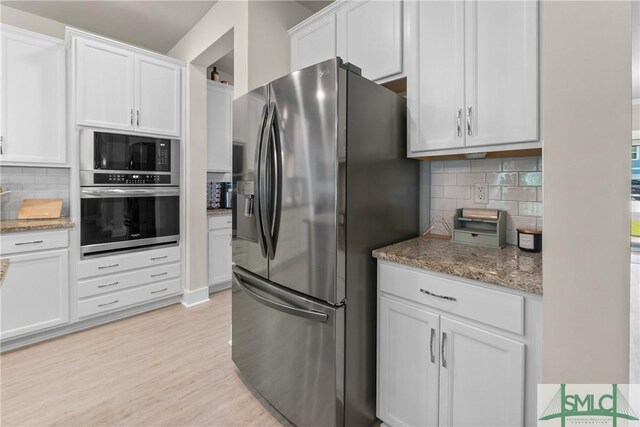 kitchen featuring light hardwood / wood-style floors, tasteful backsplash, stainless steel appliances, light stone counters, and white cabinets