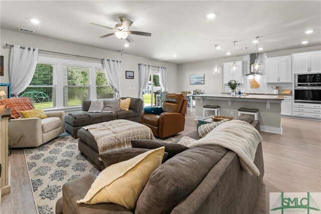 living room with ceiling fan and light hardwood / wood-style floors