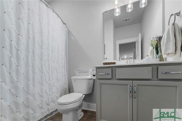 bathroom with walk in shower, vanity, toilet, and hardwood / wood-style floors