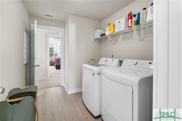 laundry room featuring light hardwood / wood-style floors and washing machine and clothes dryer