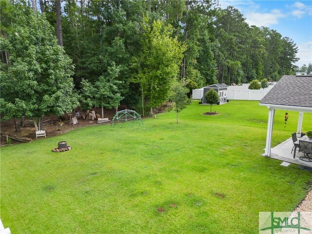 view of yard featuring a patio, a fire pit, and a storage shed