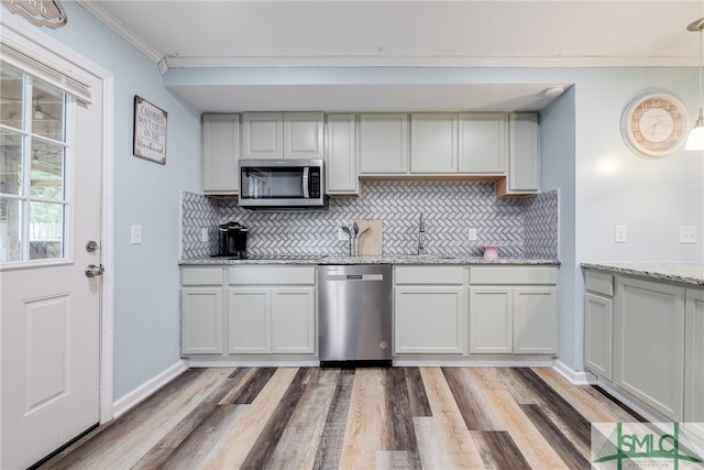 kitchen featuring appliances with stainless steel finishes, ornamental molding, tasteful backsplash, and light hardwood / wood-style flooring