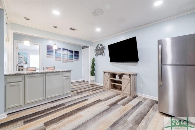 kitchen featuring pendant lighting, light hardwood / wood-style floors, crown molding, stainless steel refrigerator, and light stone counters