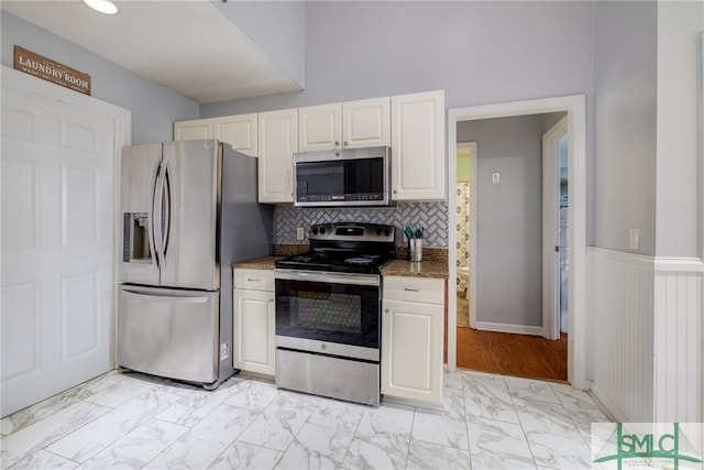 kitchen featuring tasteful backsplash, light hardwood / wood-style flooring, light stone countertops, appliances with stainless steel finishes, and white cabinets