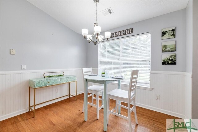 dining area with lofted ceiling, a chandelier, and light hardwood / wood-style floors