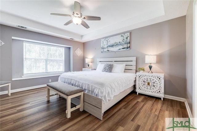 bedroom with a raised ceiling, ceiling fan, and dark hardwood / wood-style flooring