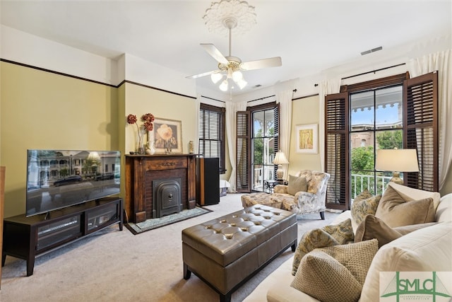 carpeted living room with a brick fireplace and ceiling fan